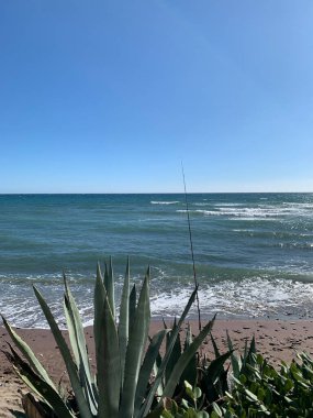 Endülüs, İspanya 'nın Costa del Sol plajından çarpıcı okyanus manzarası. Sahilde bir olta kamışı duruyor, ön planda büyük sularla, sakin bir kıyı manzarası yaratıyor..
