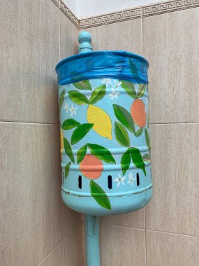 Marbella, Endülüs, İspanya 'da kiremit kaplı bir duvarda narenciye desenli elle boyanmış çöp kutusu. Mavi ve sarı sanat eserleri şehir düzenine cazibe katıyor.