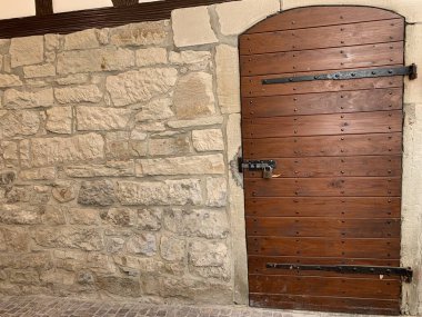 Taş bir duvarın içinde, eski ahşap bir kapı. Kırsal Alman mimarisi sergileniyor..