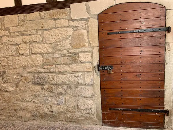 Taş bir duvarın içinde, eski ahşap bir kapı. Kırsal Alman mimarisi sergileniyor..