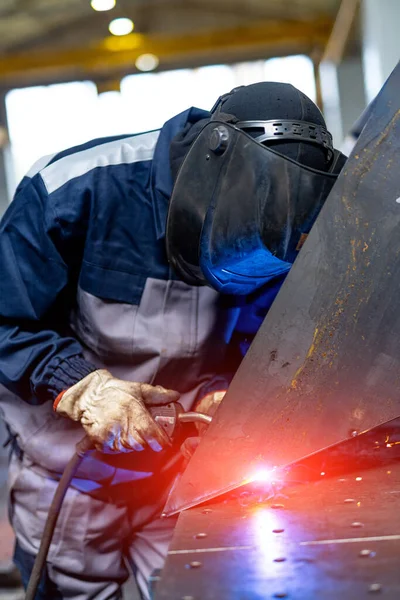 Factory worker wearing protective equipment while welding. Factory metalwork man welding.