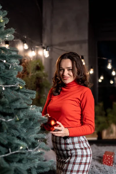 Charming lady decorating new year tree. Portrait of young lady with christmas decoration.