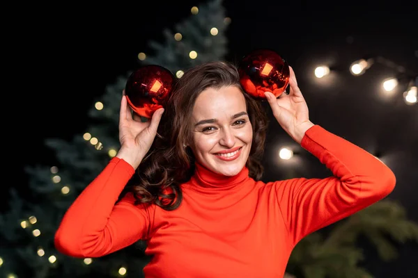Portrait of young lady with christmas decoration. Charming lady decorating new year tree.