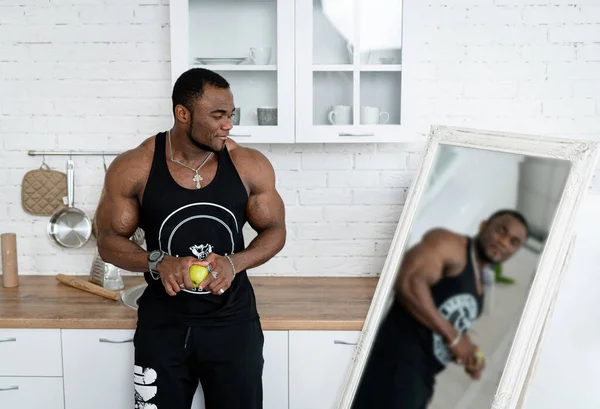 Strong muscular man standing by the mirror. Attractive young bodybuilder.