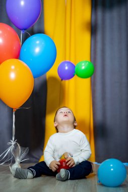 Renkli balonları olan mutlu erkek bebek. Bir çocuk bir grup balonla eğleniyor.