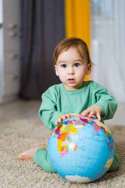 Bebek elinde bir küre tutuyor ve gelecekle ilgili hayaller kuruyor. Dünyayı keşfeden çocuk