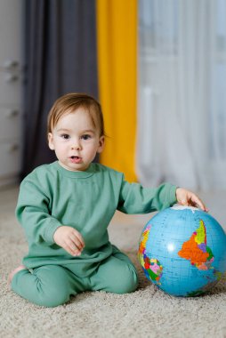 Küçük çocuk evdeki dünya modeliyle oynayarak öğreniyor. Oyun yoluyla çocuk eğitimi kavramı.