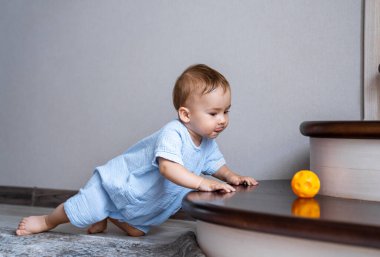 Merdivenlerde topla oynayan şirin bir bebek. Bebek renkli oyuncaklarla oynuyor. Giriş ve oturma odasının içi. Bebek için ev güvenliği.