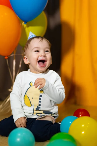 First birthday baby boy party. Smiling baby boy with bunch of colorful balloons. Birthday celebration.
