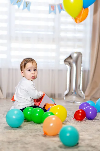 First birthday party. One year old with colorful balloons. Birthday celebration.