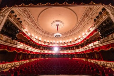 The interior of Central Golden Hall in empty theater with red seats and balcony. Luxurious theater hall in classic baroque style.