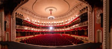 The interior of Central Golden Hall in empty theater with red seats and balcony. Luxurious theater hall in classic baroque style.