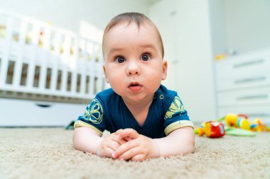 Cute happy baby boy playing toys in his child room. Beautiful baby crawls around the house