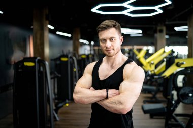 Athletic young male model with strong hands. Handsome strong man posing at the gym.