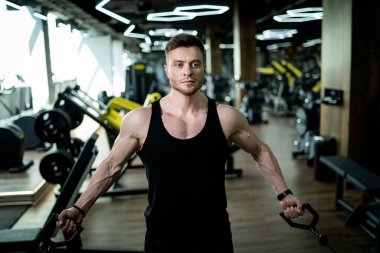 Young athletic man in gym training. Handsome bodybuilder working out.