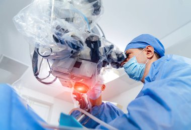 Mikroskopla operasyon. Cerrahlar ameliyat sırasında tıbbi aletler kullanırlar. Uzmanlar modern ameliyathanedeki mikroskopu inceliyor..