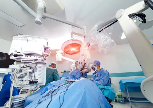 Medical team performing surgical operation in bright modern operating room. Medical devices for neurosurgery. Modern equipment in operating room.