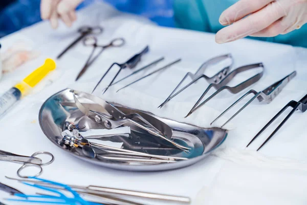 Medical tools on blur surgery background. Bowl with sterile scissors in the operating room. Close-up. Instruments for surgical procedure.