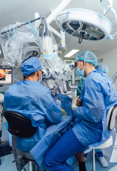 Medical team performing surgical operation in bright modern operating room. Medical devices for neurosurgery. Modern equipment in operating room.