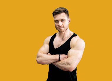 Athletic young male model with strong hands Isolated over bright yellow color background. Handsome strong man posing.