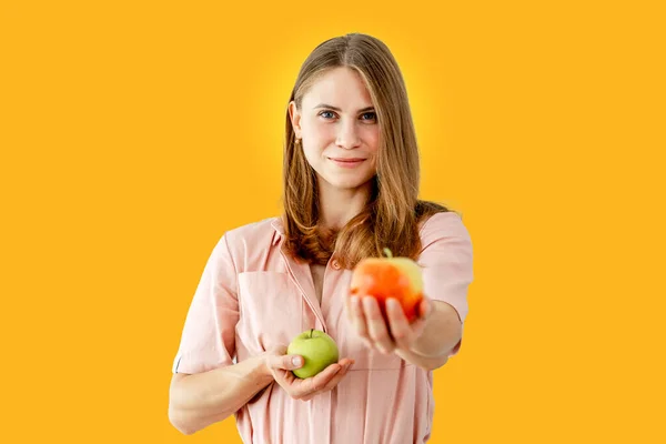 Woman is holding apples. Healthy food. Vegans. Vegetarian. Isolated on yellow background