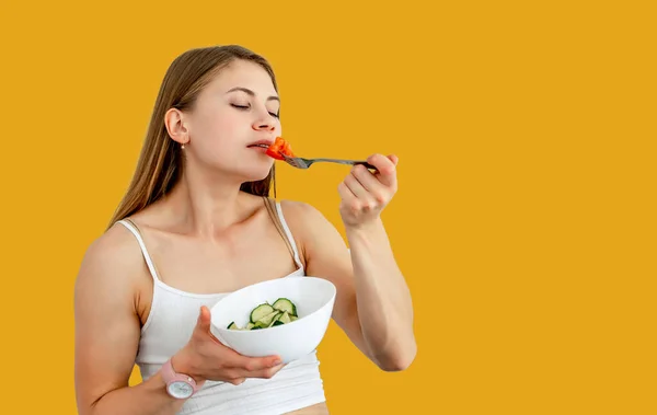 stock image Attractive woman smelling cut tomato on fork isolated on yellow studio wall. Blurred background. Healthy food and lifestyle concept. Closeup.