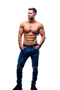 Sexual muscular man posing over white background with naked torso, hands in pockets. Muscular body and strong abs. Looking at side. Studio shot.