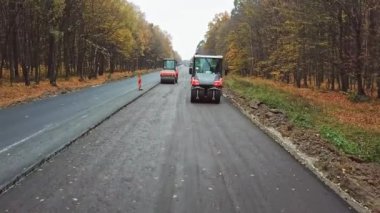 Asfalt yol inşaatı. Yeni yol inşaatında çalışan yol silindirlerinin hava manzarası