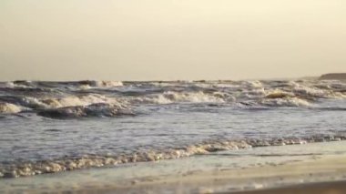 Sahilde dalga damlaları. Kumsalda köpüklü deniz suyu dalgalarını yakından izle.