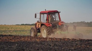 Sahada çalışan traktör. Traktör kuru bir tarlayı ekip tohumluyor.