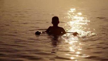 Küçük çocuk suda oynuyor. Küçük çocuk sıcak bir yaz gününde nehirde oynuyor.