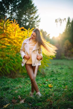 Pretty lifestyle woman walking outdoor in the park. Stylish seasonal young person outdoor.