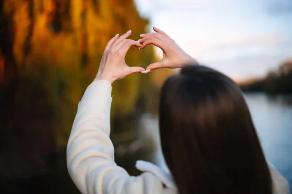 Lady showing heart by hands on nature. Gesture hands outdoor symbol.