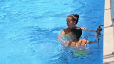 Anne havuzda, çocuğu var. Su parkındaki havuzda mutlu bir aile.