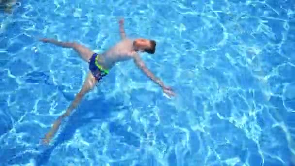 少年はプールでリラックス プールで泳いだり遊んだり — ストック動画