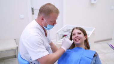 Dişçi kız dişlerini inceliyor. Dişçilik kliniğinde kadın dişlerini tedavi eden Stomatoloji doktoru