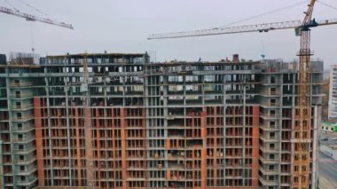 İnşaat alanının manzarası. Ağır makinelerin ve inşaat işçilerinin elektrikli aletlerle çalıştığı yeni inşaat alanının geliştirilmesi üzerinde havadan uçuş