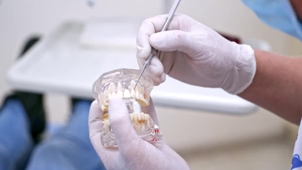 歯のモデルを示す歯科医 歯科モデルを保持する男性歯科医 患者への歯のケアを説明 — ストック動画