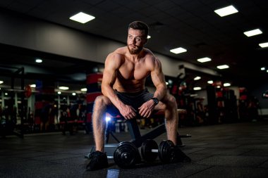 Young male athletic man working out in gym. Training muscular male person in the gym.