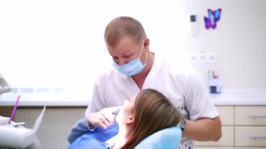 Doktor danışma hastası. Erkek dişçi kadın ağız boşluğunu kontrol ediyor.