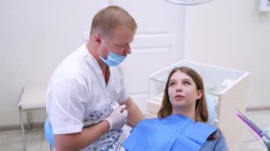 Doktor ve hasta dişçi ofisinde. Diş hekimliği koltuğundaki kadın hastaya yakından bakın.