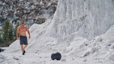 Spor adamı doğa üzerinde egzersiz yapıyor. Fizikçi, tıp topuyla doğada egzersiz yapıyor.