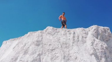 Dağda poz veren sporcu adam. Dağın tepesinde poz veren adamın havadan görünüşü