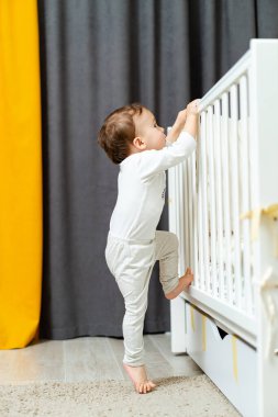 Cute little boy playing in the bed. Small child in a white bed.