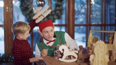 Elf oğlanla oynuyor. Elf, Noel Baba 'nın evinde küçük çocukla oynuyor.