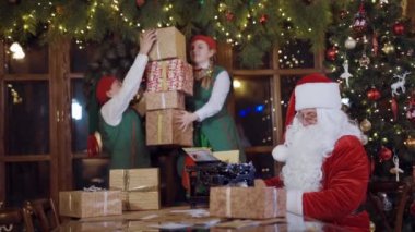 Noel Baba ve hediye kutularıyla elfler. Noel Baba ve Elfler çalışıyor