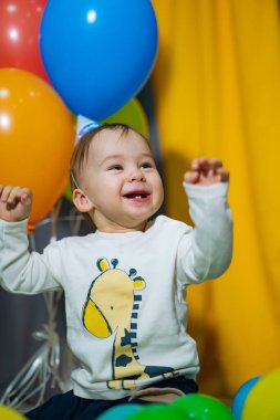 Renkli balonları olan mutlu erkek bebek. Bebek ilk doğum gününü kutluyor.