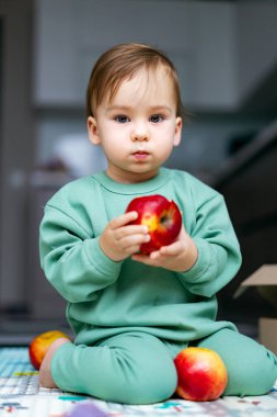 Kırmızı elmalı sevimli bir çocuk. Taze meyve tutan küçük bebek, yakın portre. Sağlık ve organik çocuk beslenme kavramı
