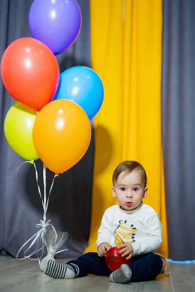 Happy baby boy with bunch of balloons. First birthday baby boy party.