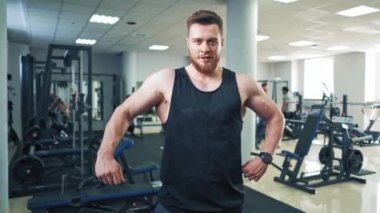 Spor salonunda beden eğitimi gören bir kadın. Güçlü kaslı vücut geliştirme sporcusu spor salonunda poz verip kaslarını şişiriyor.